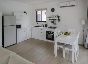 a white kitchen with a white table and a table and chairs at Zen Beach Lake Villa 3 - orchid villa in Haad Chao Phao