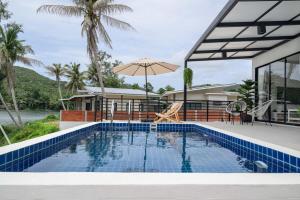 a house with a swimming pool and an umbrella at Zen Beach Lake Villa 3 - orchid villa in Haad Chao Phao