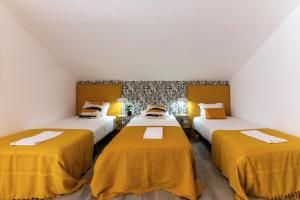 three beds in a room with yellow sheets at Carregado Second Floor in Carregado