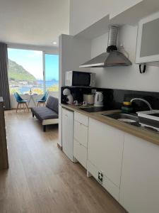 a kitchen with white cabinets and a living room at Feeling Like Home Machico in Machico