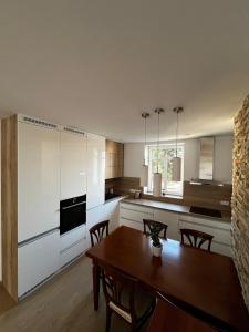 a kitchen with white cabinets and a wooden table at Baťovský dům ZLÍN in Zlín