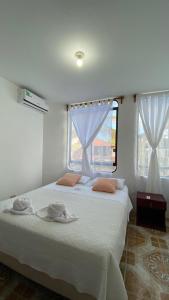 una camera da letto con un letto bianco con due asciugamani sopra di Hostal Brisas Del Mar a Puerto Villamil