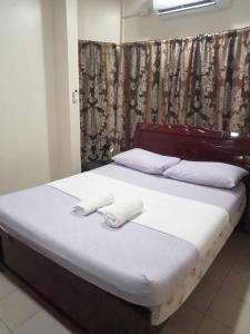 a bed with two white towels on top of it at Loidas place in Talisay