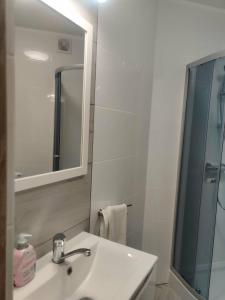 a white bathroom with a sink and a mirror at Apartament Charlie in Darlowko +14 photos