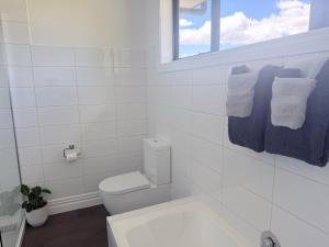 a white bathroom with a toilet and a window at Guesthouse A in Twizel