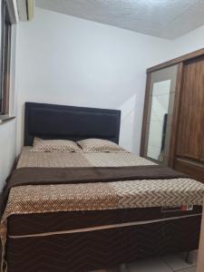a bedroom with a large bed with a wooden headboard at Apartamento Condomínio Turu a 6km da Praia in Maioba