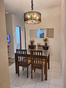 a dining room with a table and chairs and a chandelier at Apartamento Condomínio Turu a 6km da Praia in Maioba