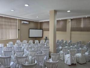 a room with rows of chairs and a screen at Hotel Ermitage in Santana do Livramento