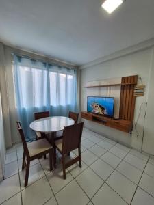 a living room with a table and chairs and a tv at Em condominio in Parnamirim +6 photos