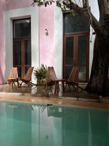 three chairs sitting in front of a house next to a pool at Hotelito DELI in Mérida