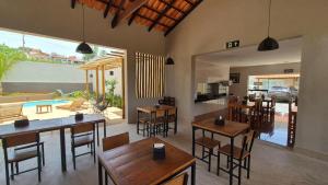 a dining room with tables and chairs and a kitchen at Pousada Carneirinho in Capitólio