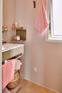 a bathroom with pink towels hanging on a wall at Camping Le Solitaire du Lac in Saint-Jorioz