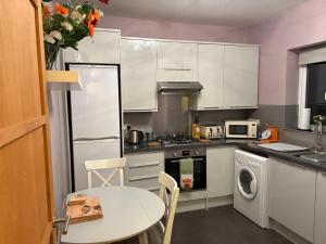 a kitchen with white cabinets and a table and a table and chairs at 13 Chute Street central and homely in Exeter