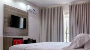 a bedroom with a bed and a television on a wall at Hotel Terceiro Milênio II in Brumado