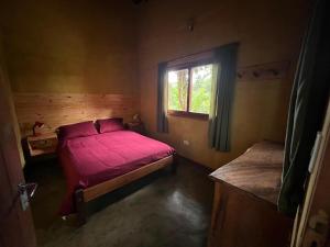 een slaapkamer met een rood bed en een raam bij Nativa Iguazu in Puerto Iguazú