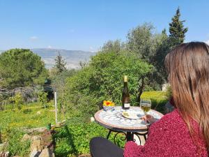 een vrouw aan een tafel met een fles wijn bij הבית ליד הבוסתן in Mikhmannim