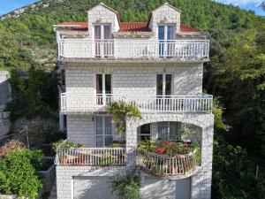 a stone house with balconies and flowers on it at Apartments Vlasic in Ston