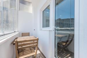 a balcony with a wooden table and chairs and a window at Apartamento da Musica - Boavista - OPENING in Porto