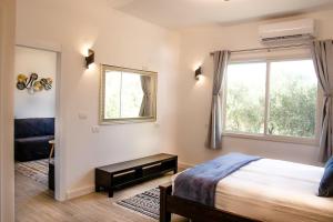 een slaapkamer met een bed en een raam bij הבית ליד הבוסתן in Mikhmannim