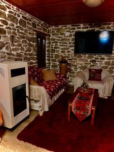 a living room with a tv and a stone wall at ΜΑΡΙΓΟΥΛΑΜ in Kalesménon