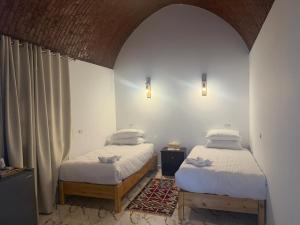 two twin beds in a room with an archway at ASKALEIH Nubian Guest House in Aswan