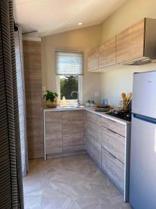 a kitchen with wooden cabinets and a white refrigerator at Camping Le Solitaire du Lac in Saint-Jorioz