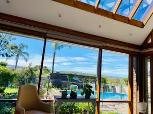 a living room with large windows looking out at a pool at Hillside Retreat with Pool in Flagstaff Hill
