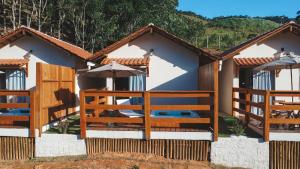 a house with a fence and an umbrella at Chalés Bermond- Rota da Ferradura in Guarapari