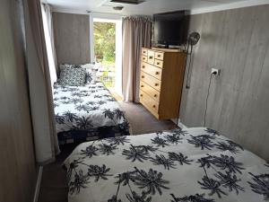 a bedroom with two beds and a dresser and a window at Wharf Street Art in Foxton