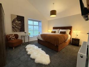 a bedroom with a bed and a chair and a white rug at The Barn in Skipton +67 photos