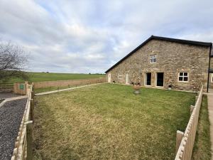 a stone barn with a large yard in front of it at The Barn in Skipton