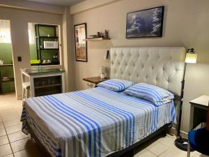 a bedroom with a bed with a blue and white striped blanket at Mini Suite Apartamento in San Pedro Sula