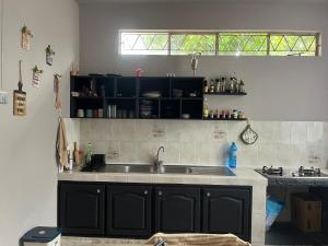 a kitchen with black cabinets and a sink at House Raghu in Rose Belle +5 photos