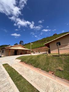 a building with a green hill in the background at Recanto das Águas in Cunha