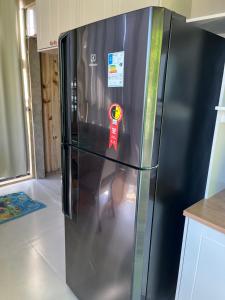 a black refrigerator with a sticker on it in a kitchen at Casa Vidro Mar in Bombinhas
