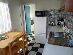 a kitchen with a table and a white refrigerator at Wharf Street Art in Foxton