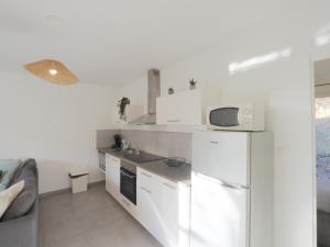a white kitchen with a sink and a refrigerator at gitelepetitvallon in Allemagne-en-Provence +2 photos