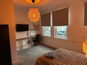 a bedroom with a bed and a tv and windows at Norton Rd Guest House in Stockton-on-Tees