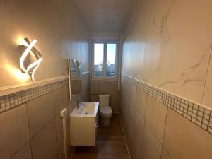 a bathroom with a toilet and a sink and a window at Mad'in Bethune in Béthune +1 photo