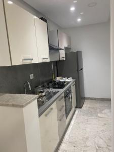 a kitchen with stainless steel appliances and white cabinets at Lux app ain zaghouen in Tunis