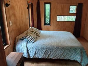 un letto in una piccola stanza con due finestre di Casa domo San Fabián de Alico a San Fabián de Alico