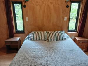 un letto in una stanza con due finestre di Casa domo San Fabián de Alico a San Fabián de Alico