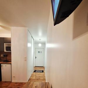 a hallway leading to a kitchen with a television on the wall at Studio ALPHA - non-smoking studio - 3min by train to Disney OR 30min walk - 5min walk to "Val d'Europe" train station in Montévrain
