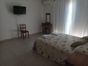 a bedroom with a bed and a tv and chairs at Casa en Ataliva Roca in Ataliva Roca