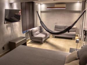 a bedroom with a hammock and chairs and a bed at Cobertura vista mar in Natal