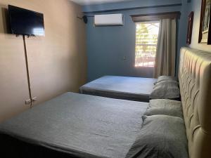 a small room with two beds and a television at Merendon Suite Apartamento in San Pedro Sula