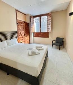 a bedroom with a large bed and a chair at Júbilus Rooms in Toledo