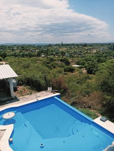 a blue swimming pool with a view of a field at Los Talitas in Villa Parque Siquiman