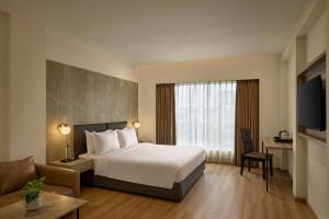 a hotel room with a white bed and a couch at The Fern Residency Ahmedabad, Subhash Bridge, Series by Marriott in Ahmedabad