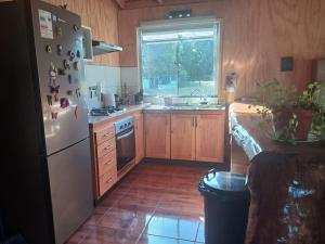 a kitchen with a white refrigerator and a sink at Casa Entre Cerros in Futrono